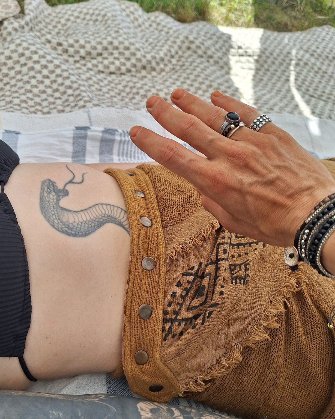 Schlangen-Tattoo als Symbol für die Kundalini Energie, während eine Hand sanft in der Nähe ruht